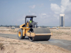 A steam roller flattens newly placed stone-base. This process is fairly early in the road construction process